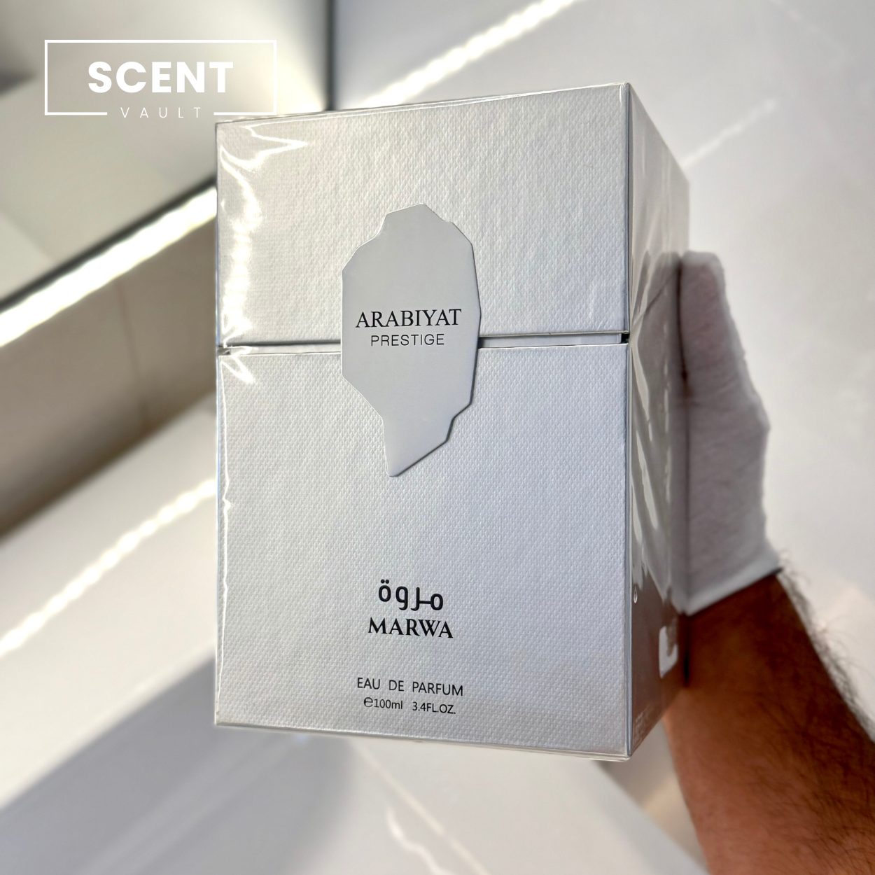 Arabiyat Prestige Marwa perfume box held by a gloved hand on a white background