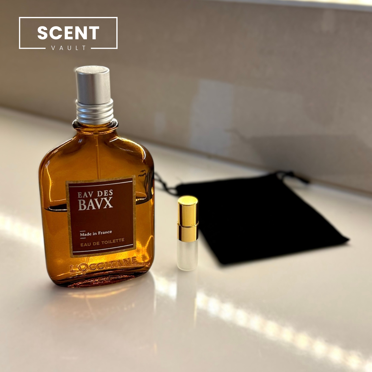 Perfume bottle labeled 'EAV DES BAVX' with a smaller bottle and black pouch on a light surface.