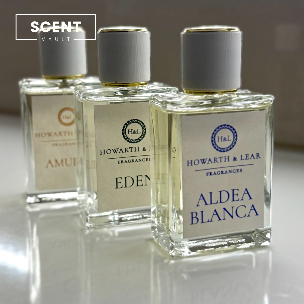 Three Howarth & Lear fragrances bottles labeled 'Amul', 'Eden', and 'Aldea Blanca' on a reflective surface.