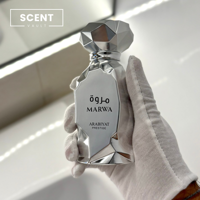 Silver perfume bottle labeled 'Marwa' held by a gloved hand with 'Scent Vault' branding.