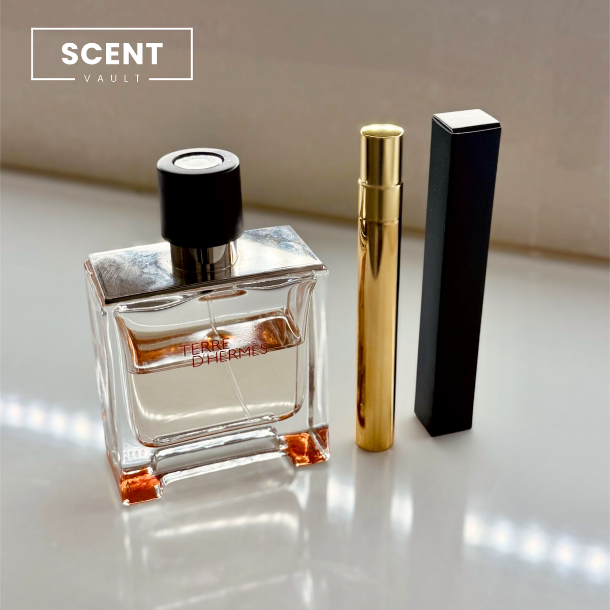 Hermès Terre d'Hermès Parfum 10ml gold decant atomiser and black gift box beside the full bottle - Scent Vault